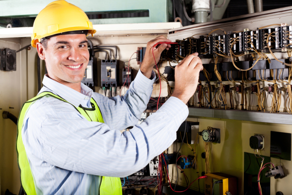 happy male electrician working on industrial machine